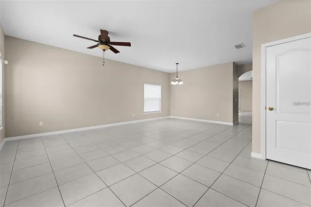 an empty room with windows and ceiling fan