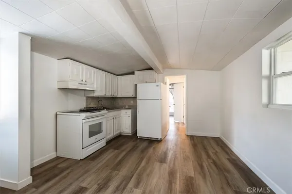 a kitchen with wooden floors and white stainless steel appliances