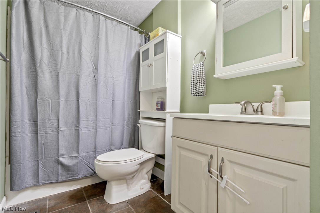 1547 Sunnyacres Road Akron, OH 44321 - Photo 13 of 23 Bathroom with vanity with extensive cabinet space, dark tile flooring, mirror, and a textured ceiling