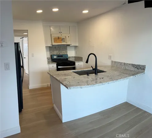 a kitchen with granite countertop a refrigerator and a stove top oven