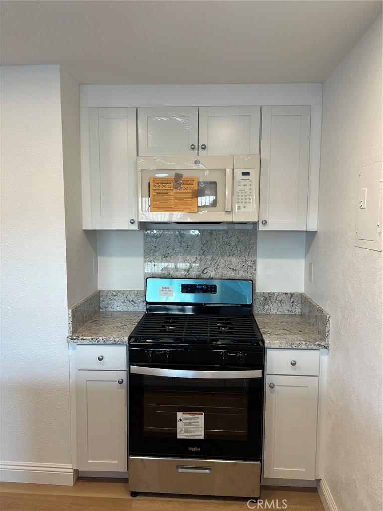 2255 Cahuiila Street, Unit 73 Colton, CA 92324 - Photo 9 of 12 a kitchen with stainless steel appliances granite countertop white cabinets a stove a microwave and a refrigerator