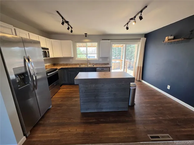 a kitchen with kitchen island granite countertop a sink stove and refrigerator
