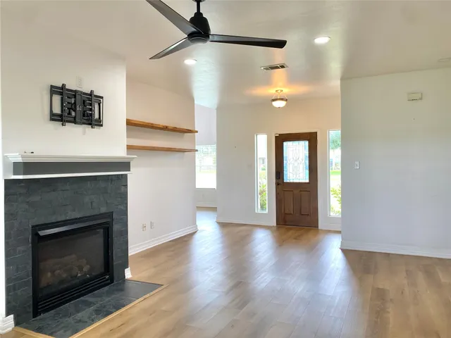 a view of an empty room with wooden floor and a fireplace