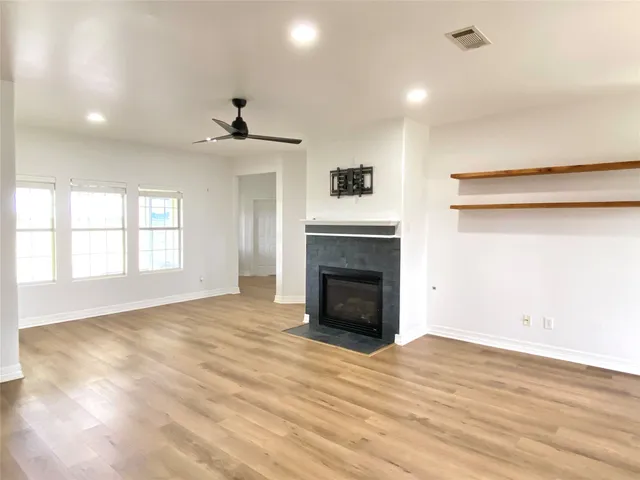 a view of empty room with wooden floor and fireplace
