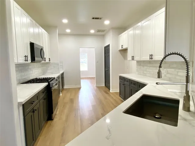 a kitchen with stainless steel appliances granite countertop a sink a stove and a wooden floors