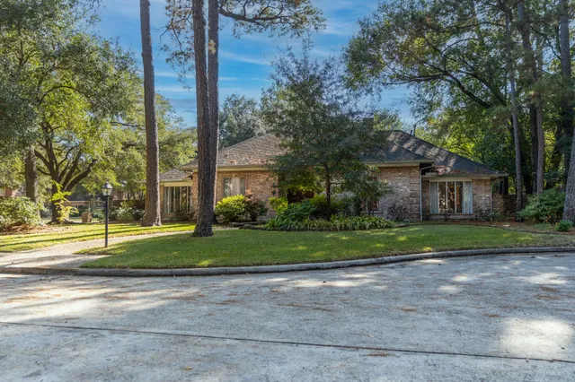 a front view of a house with a yard and large trees