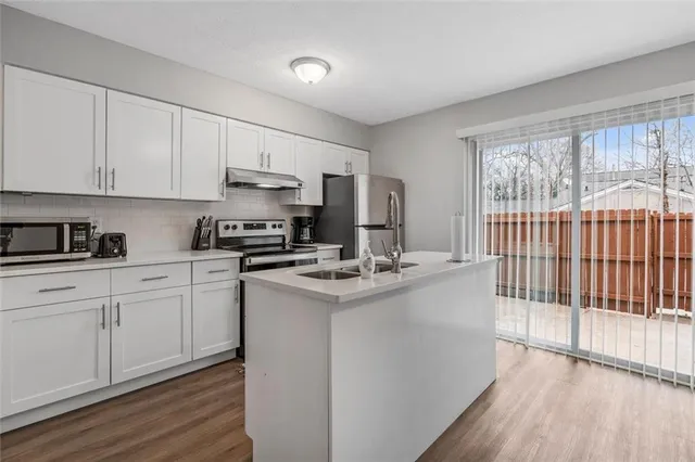 a kitchen with kitchen island granite countertop a sink cabinets and wooden floor
