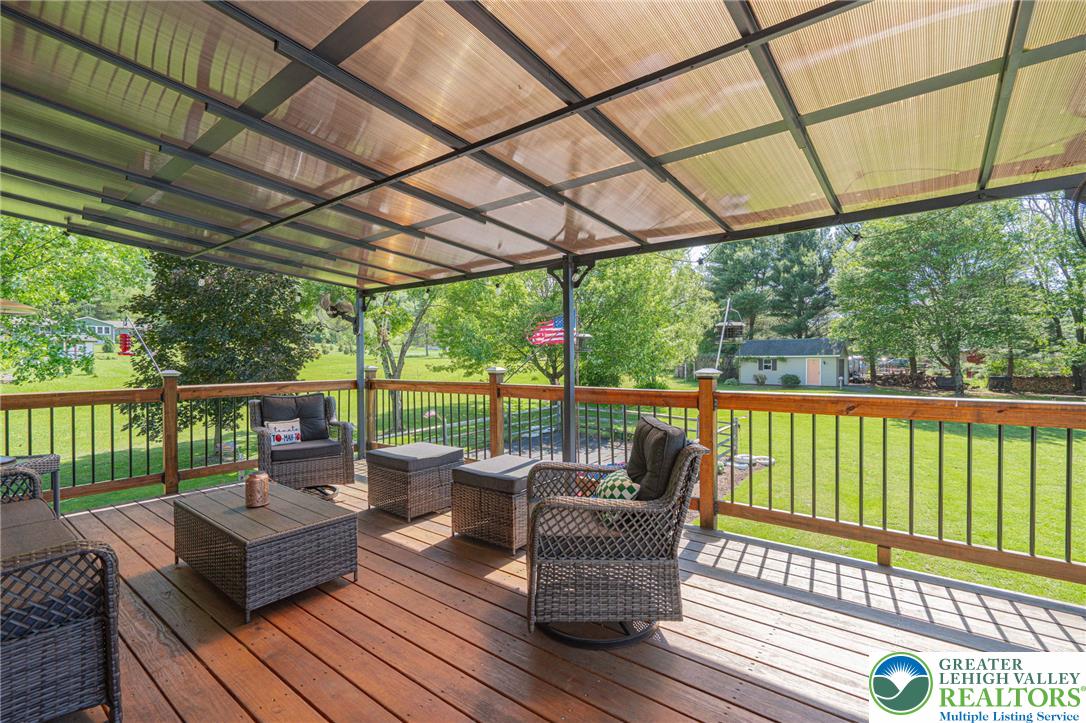 341 Lower Greenhill Road Kunkletown, PA 18058 - Photo 43 of 69 A spacious wooden deck provides ample outdoor living under a protective translucent roof, overlooking a vibrant green lawn.