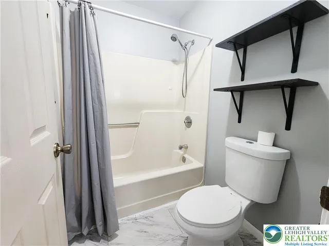 a white toilet sitting next to a bath tub