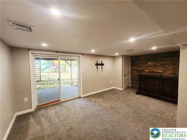 an empty room with kitchen view and a refrigerator