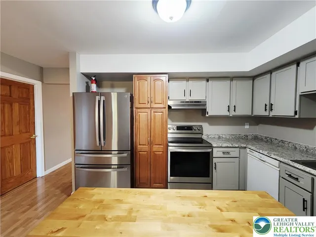 a kitchen with granite countertop a refrigerator and a stove top oven