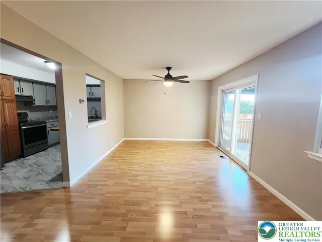 a view of a livingroom with wooden floor and a kitchen