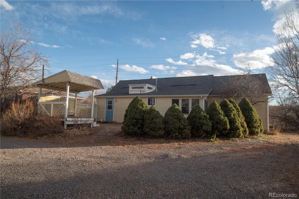a view of a blue house with a yard and sitting area