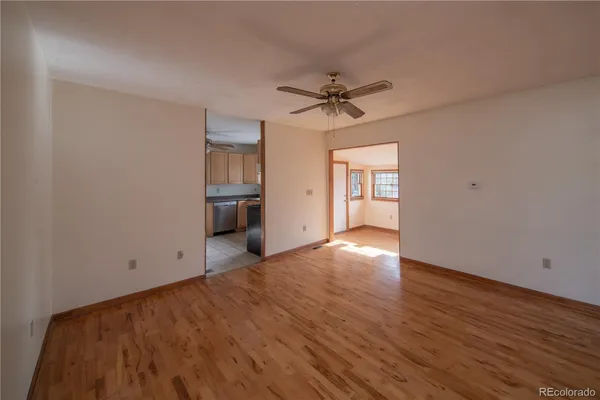 a view of empty room with wooden floor and ceiling fan