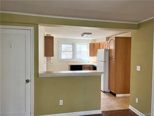 a view of a kitchen with a refrigerator wooden floor and a window