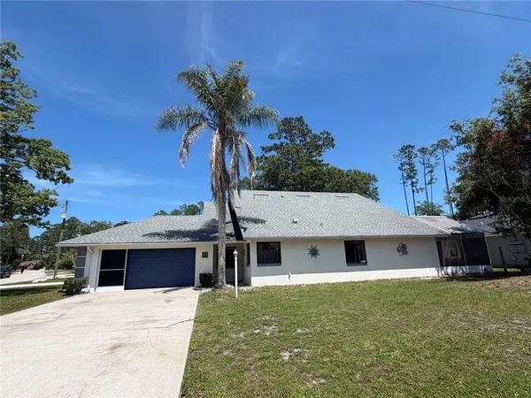 a front view of house with yard and trees in the background