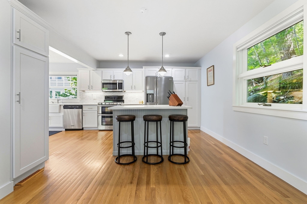 35 Keyes Road Westford, MA 01886 - Photo 12 of 40 a open kitchen with stainless steel appliances granite countertop a stove top oven a sink dishwasher and a dining table with wooden floor