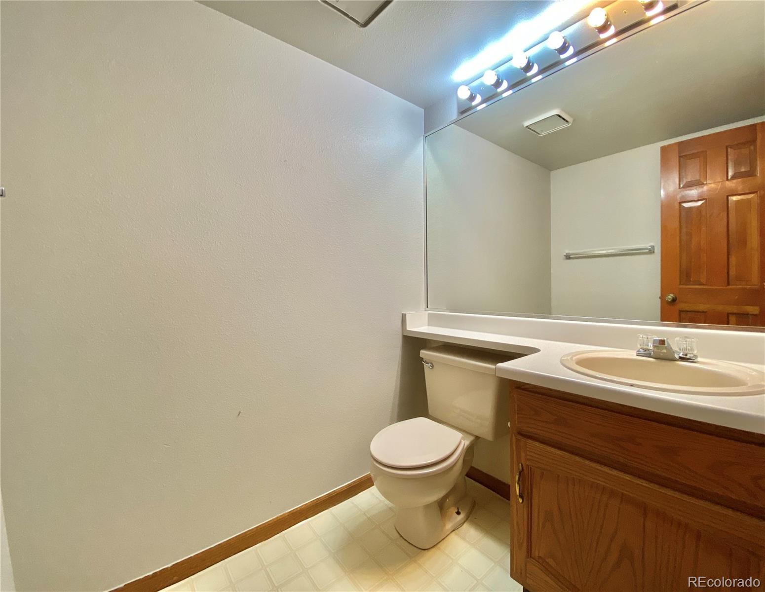 9393 Princeton Street Highlands Ranch, CO 80130 - Photo 14 of 18 a bathroom with a toilet a sink and mirror