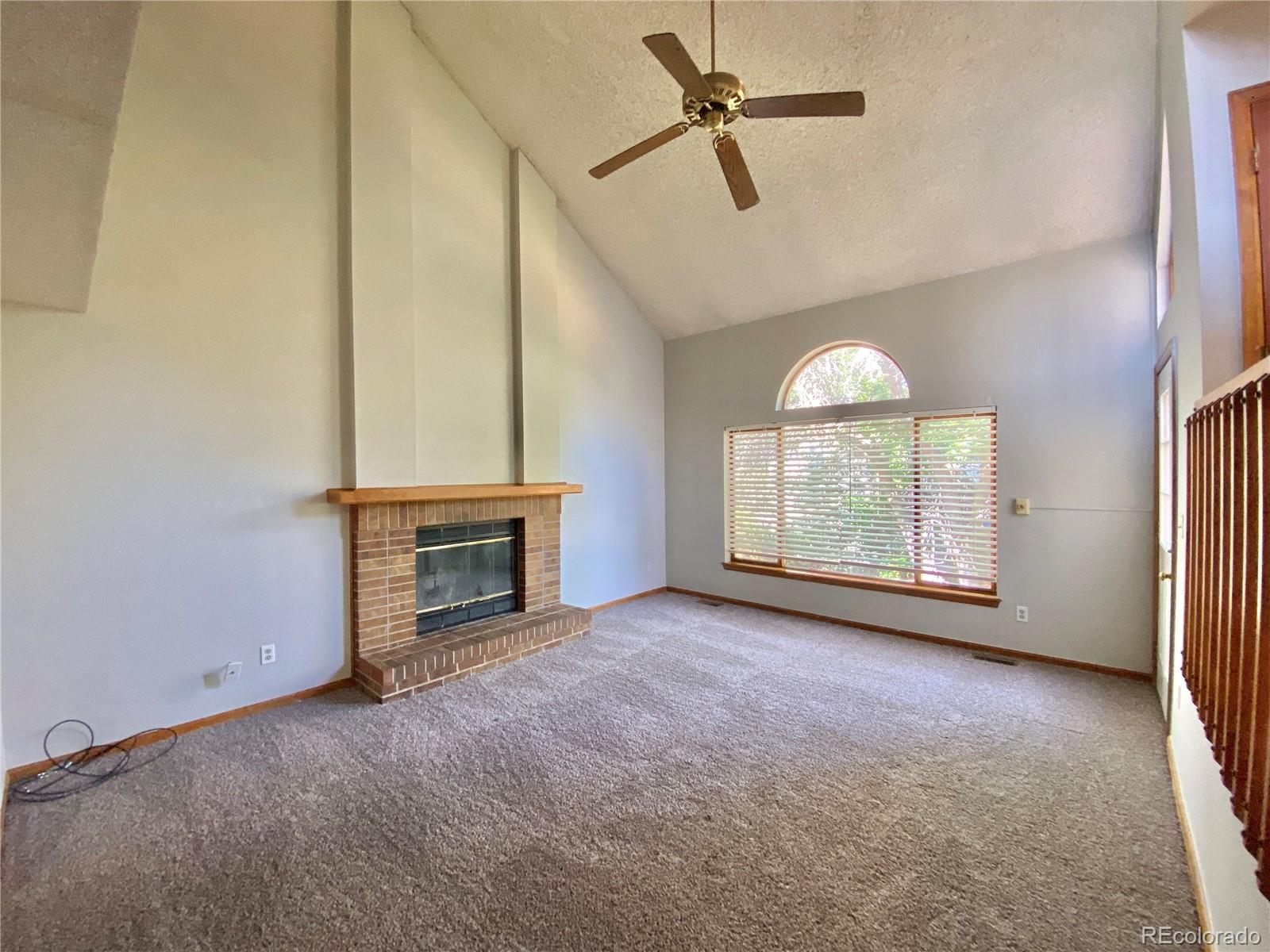9393 Princeton Street Highlands Ranch, CO 80130 - Photo 6 of 18 an empty room with windows fireplace and a ceiling fan