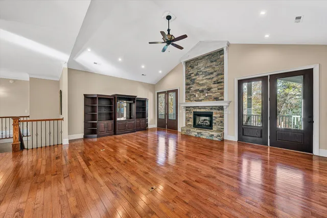 a kitchen with stainless steel appliances granite countertop a stove a sink dishwasher a refrigerator white cabinets and wooden floor next to a window