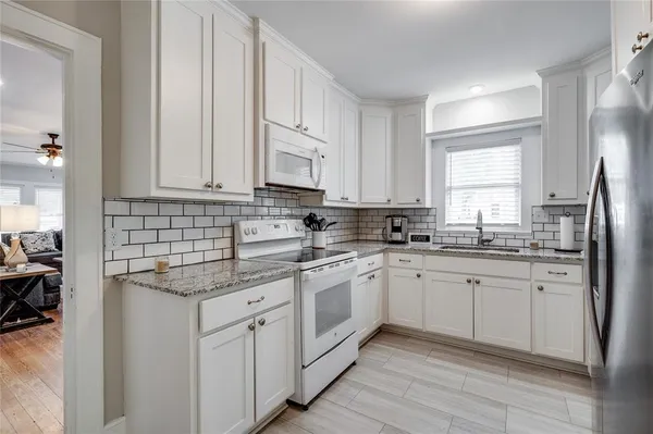 a kitchen with granite countertop white cabinets and white appliances