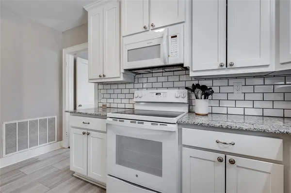 a kitchen with granite countertop white cabinets and white appliances