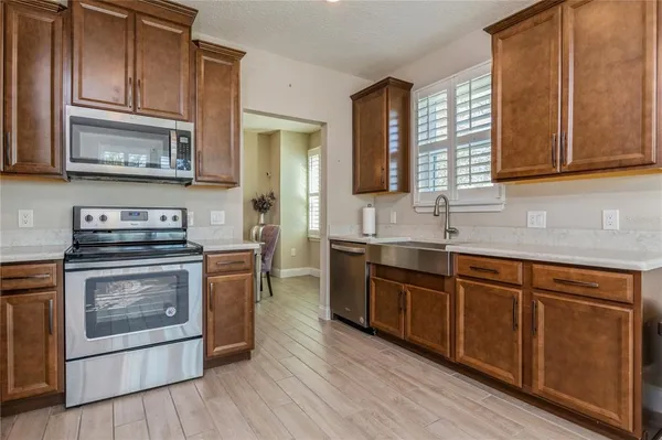 a kitchen with stainless steel appliances granite countertop a stove a sink dishwasher and a microwave oven with wooden cabinets