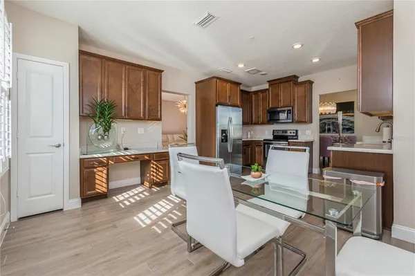 a kitchen with stainless steel appliances kitchen island granite countertop a refrigerator a stove top oven a sink and a dining table with wooden floor