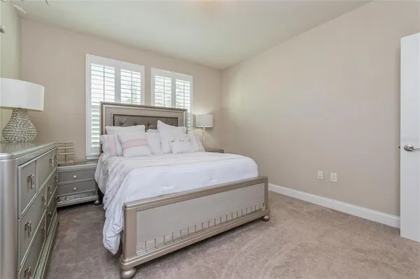 a bedroom with a bed and a lamp on dresser