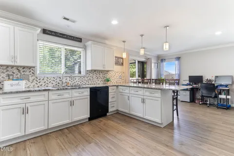 a kitchen with granite countertop a sink cabinets and wooden floor