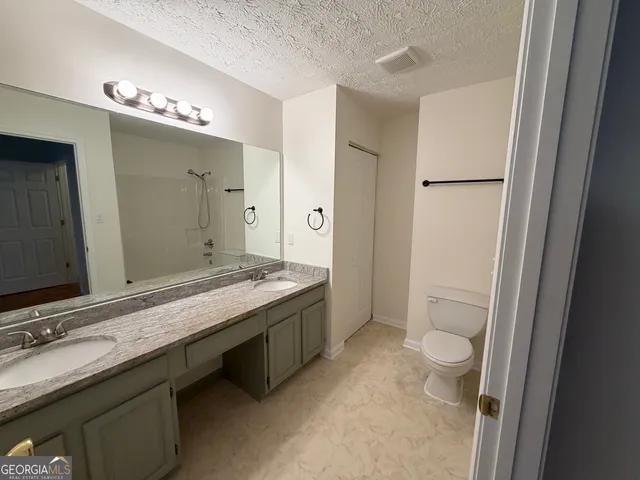 a bathroom with a granite countertop sink a toilet and a mirror