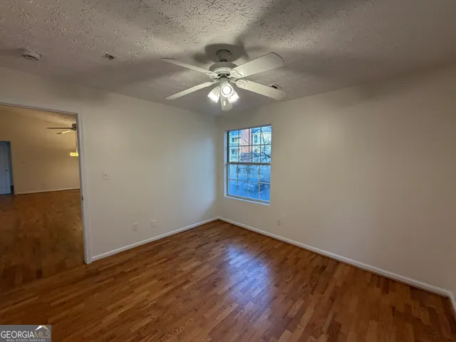 a view of an empty room with window and wooden floor