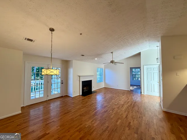 a view of a room with wooden floor a ceiling fan and a window