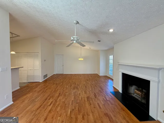 a view of empty room with wooden floor and fireplace
