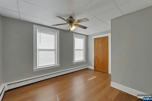 an empty room with wooden floor fan and windows