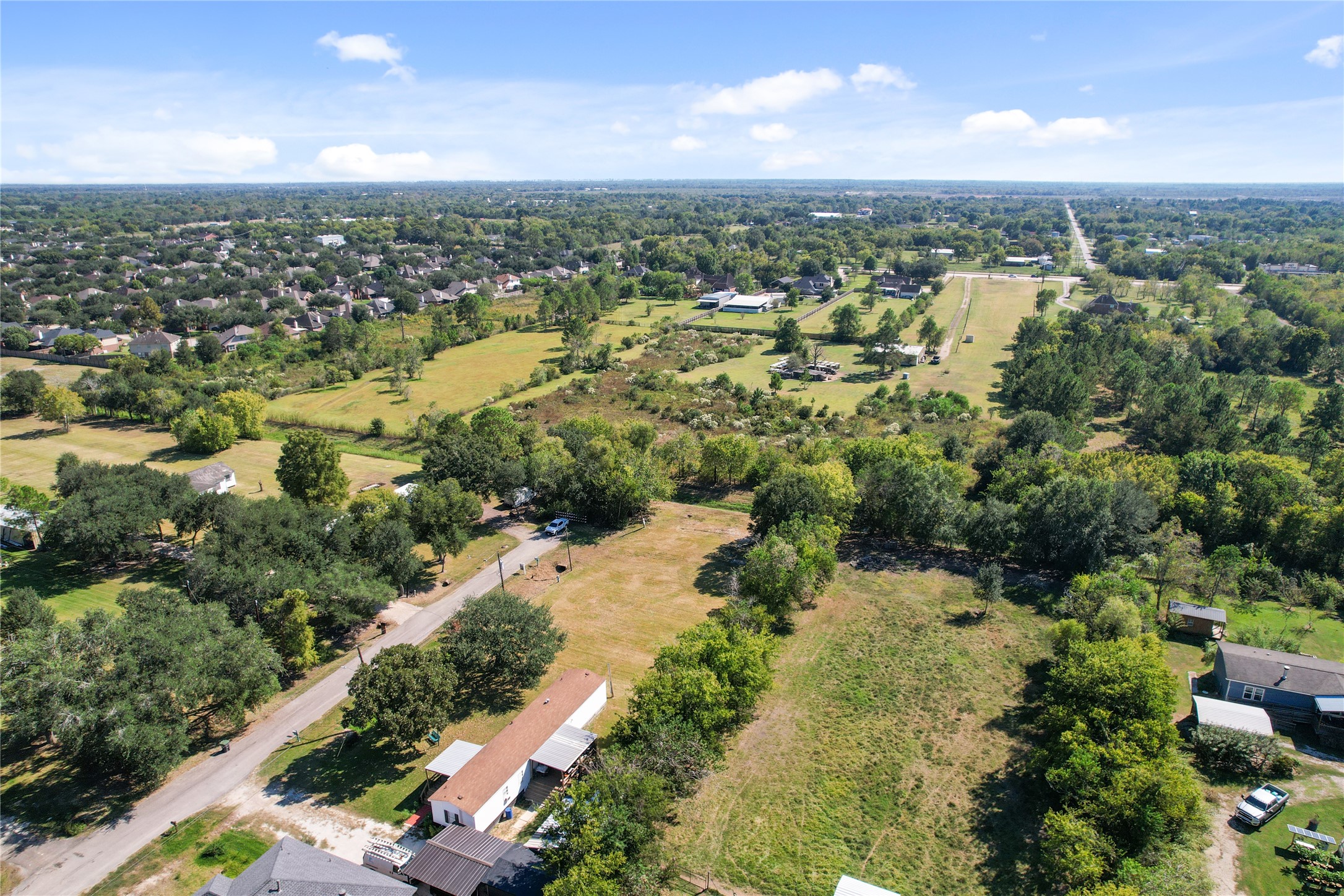 an aerial view of residential houses with outdoor space and trees