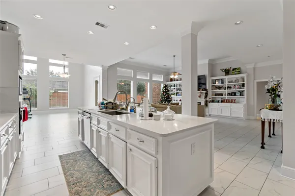 a large white kitchen with kitchen island a sink a stove a dining table and chairs