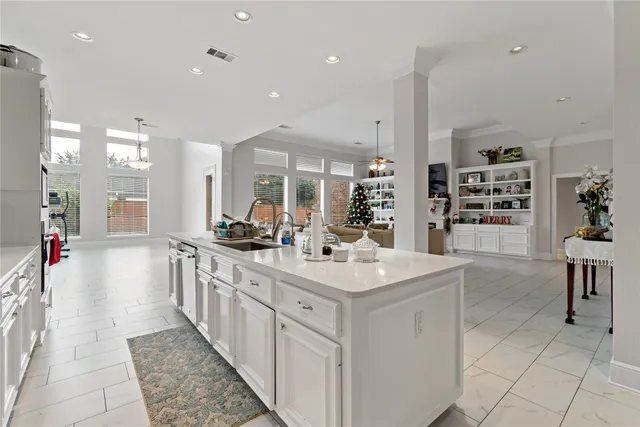 a large white kitchen with kitchen island a sink a stove a dining table and chairs