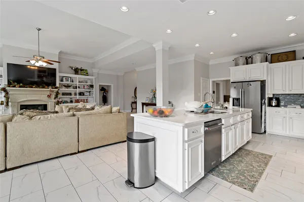 a kitchen that has a lot of white cabinets and stainless steel appliances