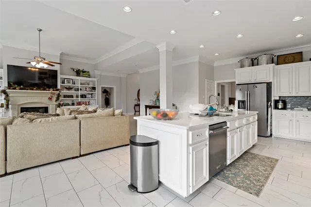 a kitchen that has a lot of white cabinets and stainless steel appliances