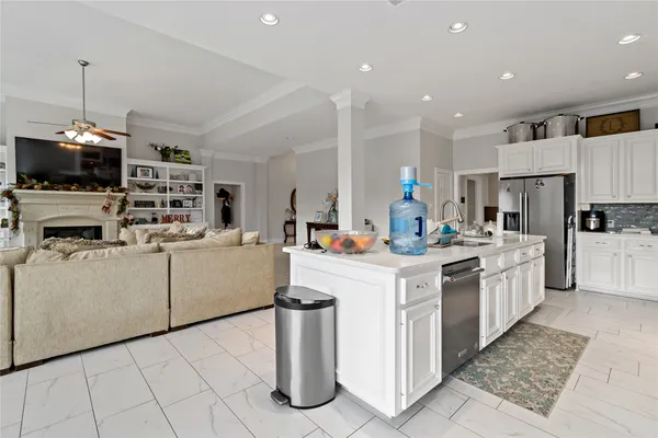 a kitchen that has a lot of white cabinets and stainless steel appliances