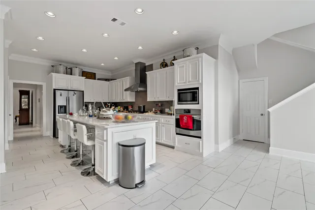 a kitchen that has a lot of white cabinets and stainless steel appliances