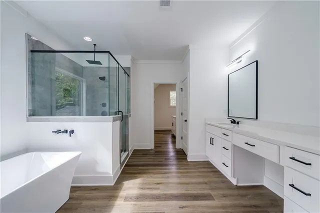 a bathroom with a double vanity sink a large mirror a bathtub and next to a window