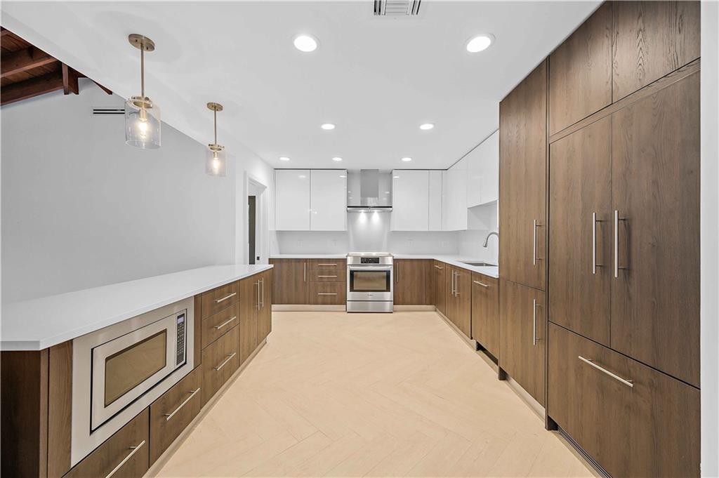 2201 Intracoastal Drive Fort Lauderdale, FL 33305 - Photo 11 of 35 a large kitchen with stainless steel appliances kitchen island a large counter top and wooden floors