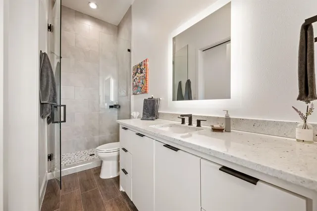a bathroom with a granite countertop sink a toilet and a large mirror