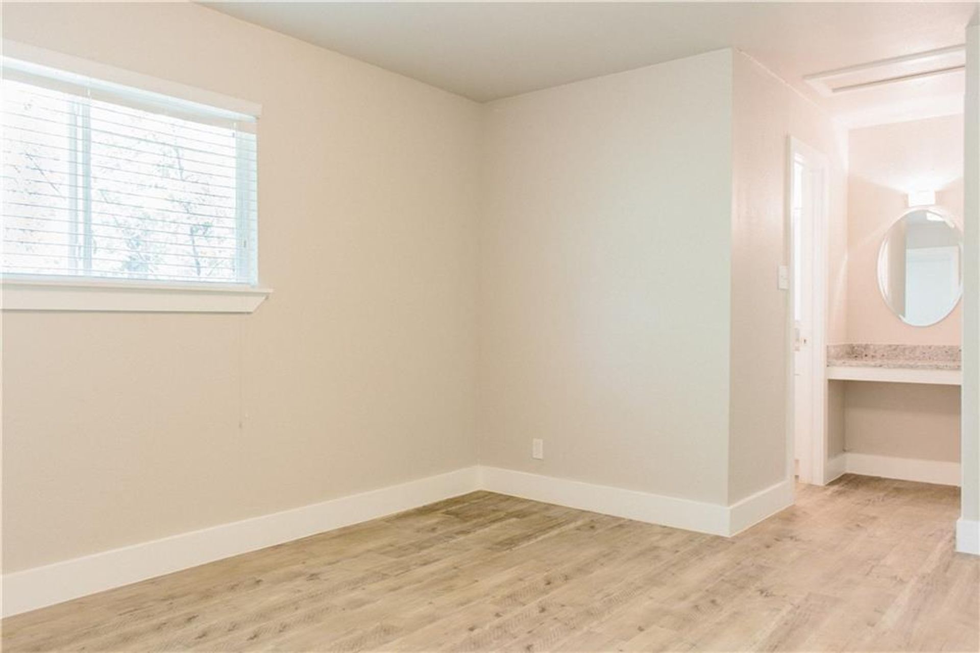 1302 East 52nd Street, Unit 101 Austin, TX 78723 - Photo 3 of 8 an empty room with a window and wooden floor