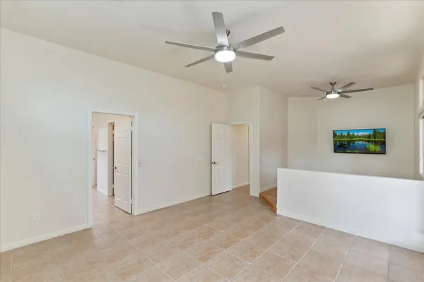 an empty room with ceiling fan and windows