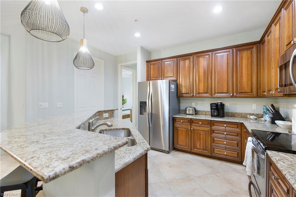 8975 Malibu Street, Unit 1304 Naples, FL 34113 - Photo 10 of 43 a kitchen with stainless steel appliances granite countertop a sink refrigerator and microwave