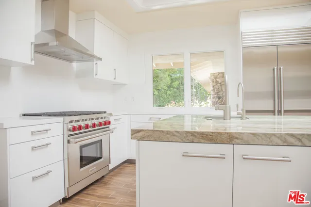 a kitchen with granite countertop stainless steel appliances white cabinets and a window