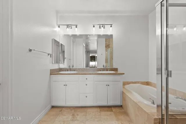 a spacious bathroom with a granite countertop sink a mirror and bathtub